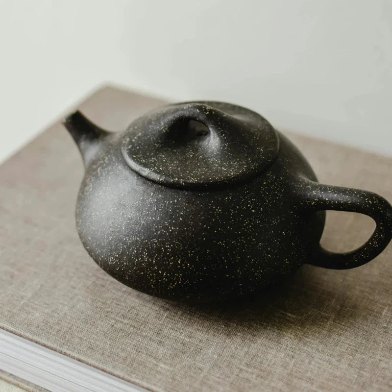 Petite Théière posée sur un tissu beige 