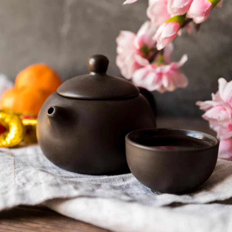 théière avec tasse dans un décor avec des fleurs 