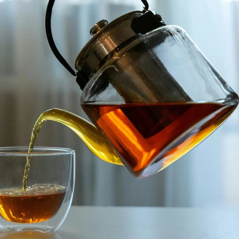 théière avec infuseur versant du thé dans une tasse 