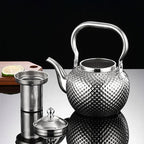 Grande Théière Argentée avec Infuseur 1,2 L — 2 L sur une table en verre