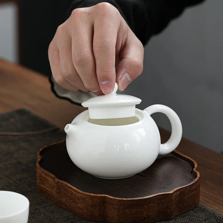 Théière Blanche chinoise en céramique main qui retire le couvercle 