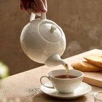 Théière Blanche en Porcelaine Blanche versant du thé dans une tasse 