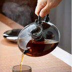 Théière Induction en Verre Borosilicate  versant du thé dans une tasse 