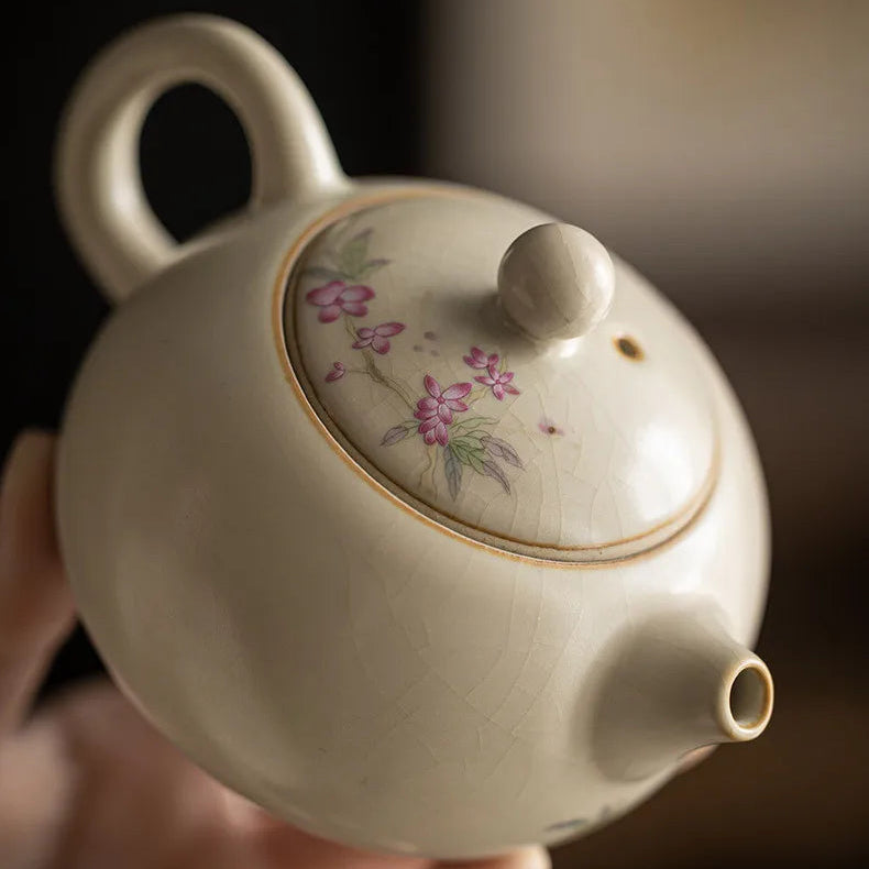Théière Porcelaine Artisanale Fleurie au premier plan dans une main 