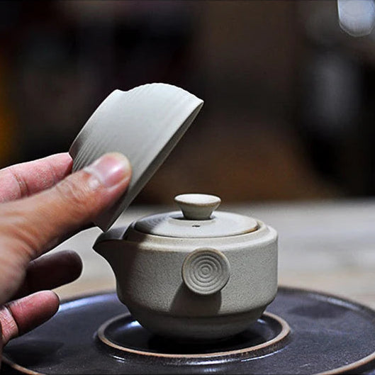 Théière Solitaire Style Japonais avec la tasse qui s'est faite retiré par une main 