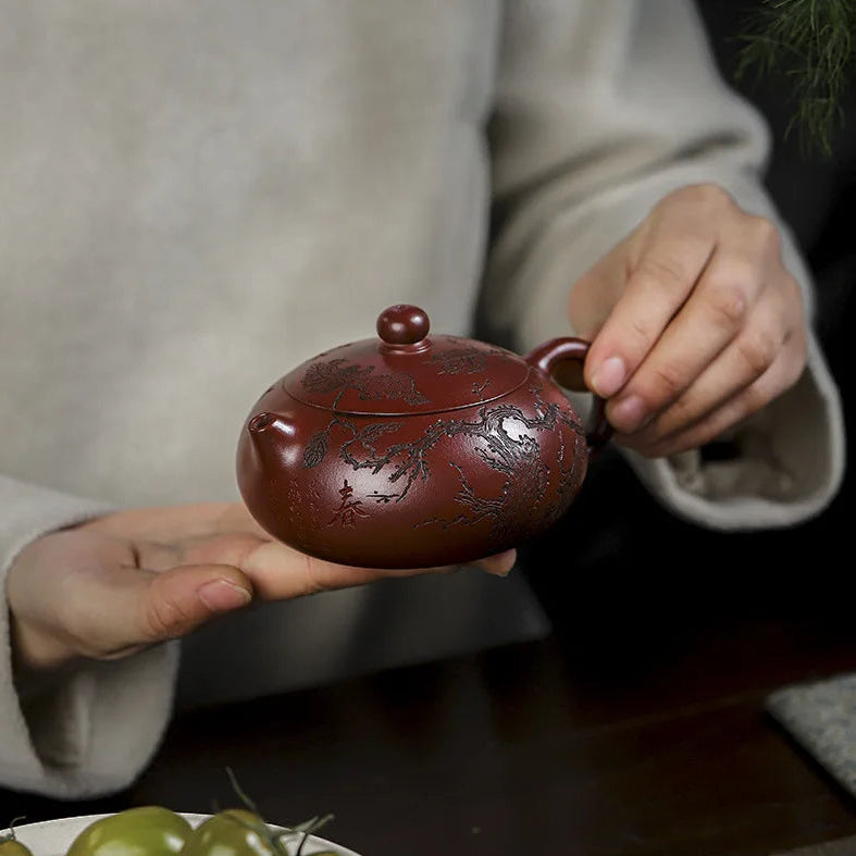 Théière Yixing Gravée Faite Main tenu par une personne 