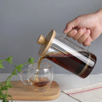 Théière à Piston en verre borosilicate versant du thé dans une tasse 