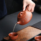 Théière avec Filtre en Terre Cuite Orange versant du thé dans une tasse 