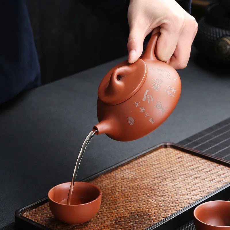 Théière avec Filtre en Terre Cuite Orange versant du thé dans une tasse 