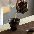 théière en grès versant du the dans une tasse 