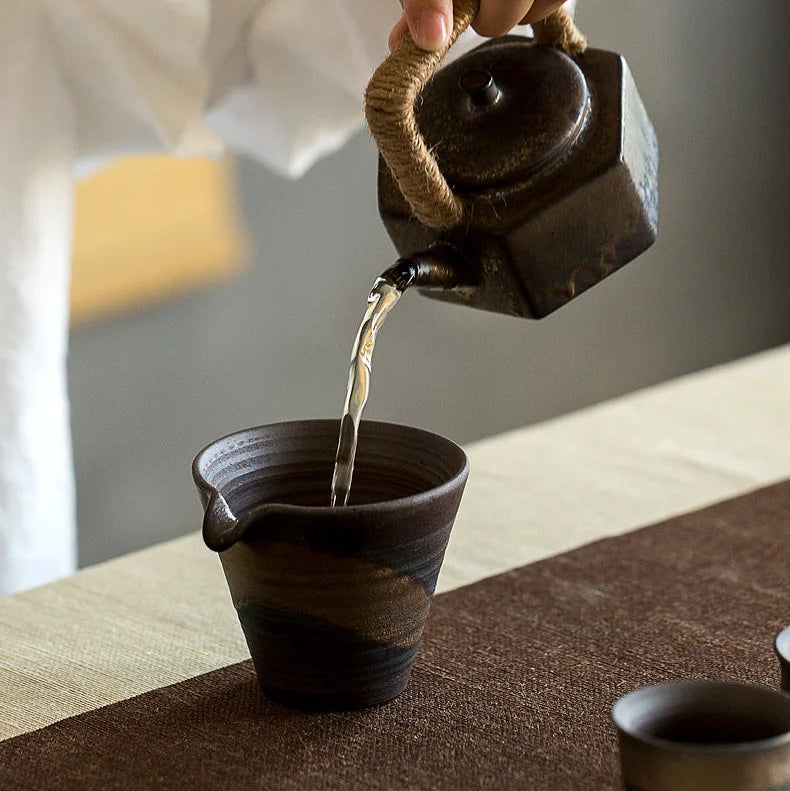 théière en grès versant du the dans une tasse 