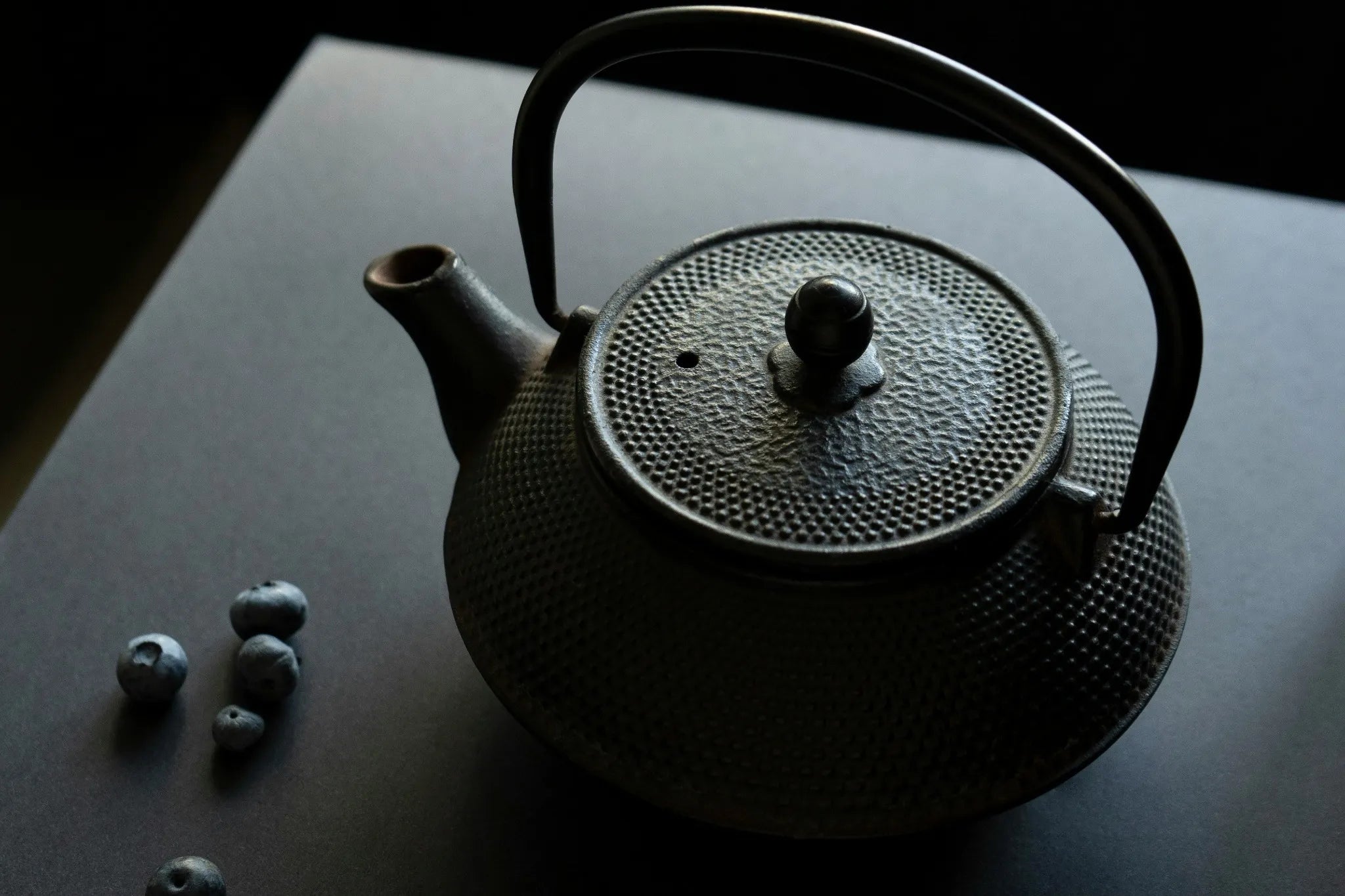 théière en fonte noir dans un décor sombre avec une source de lumier 